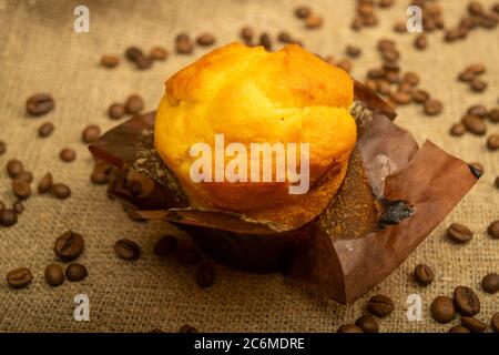 Fresh cupcake and coffee beans on a homespun fabric with a rough texture. Close up Stock Photo