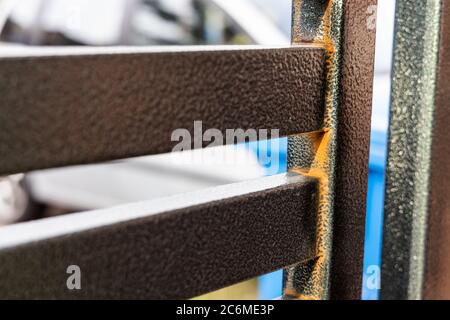 Rust forming on non galvanized outdoor epoxy painted steel metal gate Stock Photo