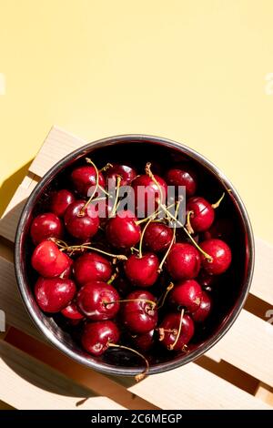 Fresh cherry in bowl on wooden yellow background. fresh ripe cherries. sweet summer berries.Template useful seasonal red fruits for design and Stock Photo