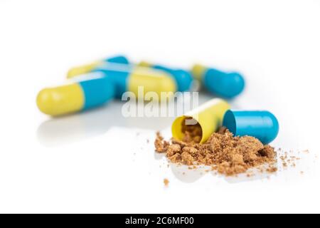 Close-up of opened medicine capsule revealing powder active drugs ingredients, in white background Stock Photo
