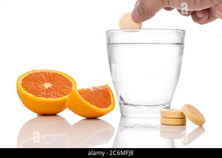 Series of orange flavored vitamin c effervescent tablet dropped and dissolve in glass of water on white background Stock Photo