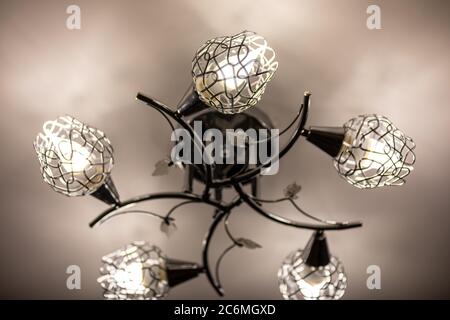 Metal ceiling chandelier with with five shades, in which are installed LED light bulbs. Economical home lighting. Energy saving concept. Stock Photo