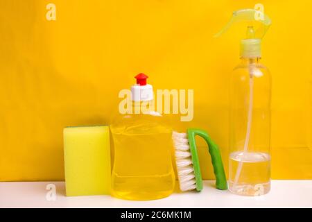 Set for cleaning various surfaces in the kitchen, bathroom and other areas. In yellow on the background . Concept of home cleaning services. Front view. Stock Photo