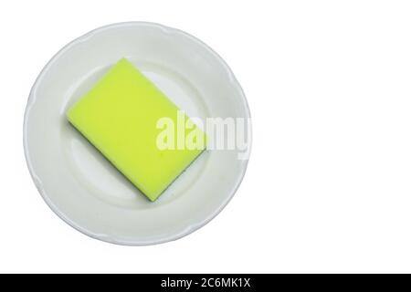 White plate on a white background isolated. With a yellow dish sponge in it. Copyspace Stock Photo