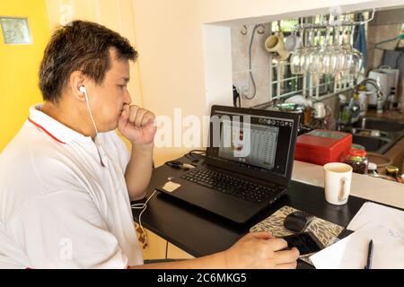 Matured Asian business man work from home listening to video conference presentation call with colleagues. Stock Photo