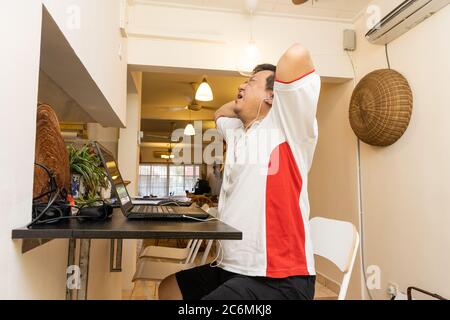 Matured Asian business man with both hands on head in stressful expression in work from home video conference call in Malaysia Stock Photo