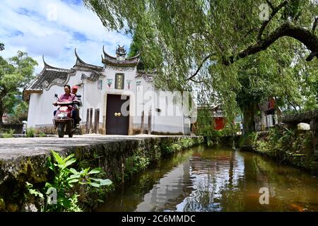 (200711) -- FUZHOU, July 11, 2020 (Xinhua) -- Villagers pass by the Zheng Ancestral Hall, a historic architectural site, in Puyuan Village, Puyuan Township, Zhouning County, southeast China's Fujian Province, July 4, 2020.  At the first glance, Puyuan Village appears no difference from other historical villages in China. But it's the carp fish in a local creek, known as the Carp Brook, that make the village special.     Puyuan village covers an area of 9.2 square kilometers and has a population of about 6,200. Originated from the Ziyun Mountain, several streams converge into the 3,000-meter-lo Stock Photo