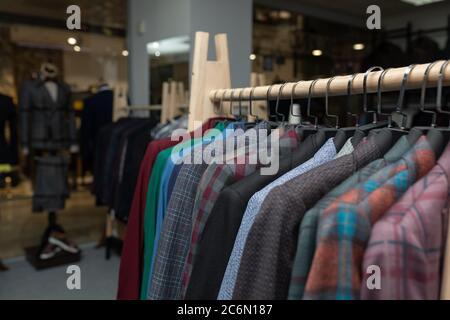 expensive men's clothing store. a row of jackets on hangers. shoping sale background theme. clothes on hanger in shop Stock Photo