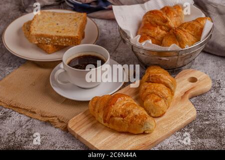freshly baked croissants and whole wheat bread with black coffee on grey table for breakfast Stock Photo