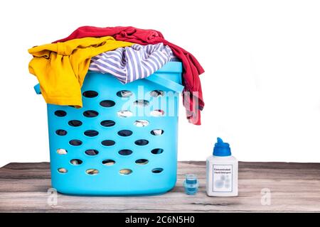 Compact concentrated laundry liquid detergent next to basket full of apparels on white background Stock Photo