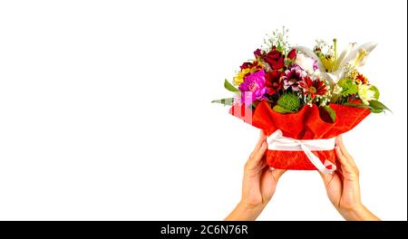 Women's hands holding colorful bouquet of flowers. Composition of various flowers in wrapping basket on isolated white background. Stock Photo