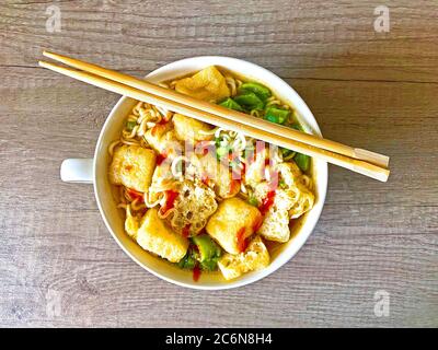 Bowl of spicy Asia seafood noodle soup with sliced fried tofu Stock Photo