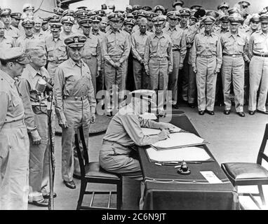 Surrender of Japan, Tokyo Bay, Sept. 2, 1945. Fleet Adm. Chester W. Nimitz, U.S. Navy, signs the Instrument of Surrender as United States representative, aboard USS Missouri (BB-63), Sept. 2, 1945. Standing directly behind him are (left-to-right): General of the Army Gen. Douglas MacArthur; Adm. William F. Halsey, U.S. Navy, and Rear Adm. Forrest Sherman, U.S. Navy. (U.S. Navy photo, Photo #: 80-G-701293) Stock Photo