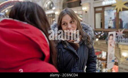 The meeting of the girlfriends. Two women are discussing something in a shopping center. Stock Photo