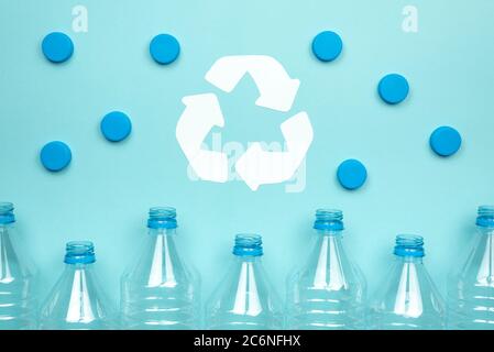 Horizontal color image with a front view of a clear plastic bottles with caps on a blue background. Recycling and environment concept. Stock Photo