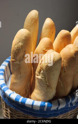 Wicker basket in which there are several loaves of white flour bread the whole set isolated on a neutral background Stock Photo