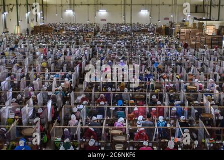 Malang, Indonesia. 11th July, 2020. Workers package cigarettes at Gudang Baru cigarette factory in Malang, East Java, Indonesia, July 11, 2020. Workers wearing face masks work with bordering plastic shields amid the COVID-19 outbreak. Credit: Aman R./Xinhua/Alamy Live News Stock Photo