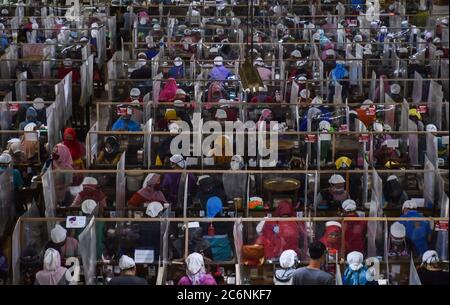 Malang, Indonesia. 11th July, 2020. Workers package cigarettes at Gudang Baru cigarette factory in Malang, East Java, Indonesia, July 11, 2020. Workers wearing face masks work with bordering plastic shields amid the COVID-19 outbreak. Credit: Aman R./Xinhua/Alamy Live News Stock Photo