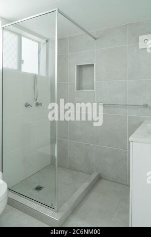 Small ensuite bathroom with show recess and tiled walls Stock Photo