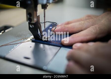A man sews from leather on a sewing machine. Hands and sewing.  Stock Photo
