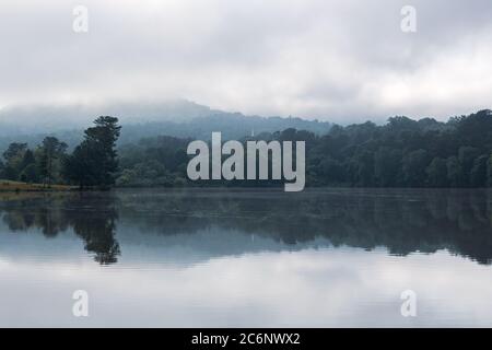 Morning fog softens the mountains in the distance, all reflected in Beaver Lake in Asheville, NC, USA Stock Photo