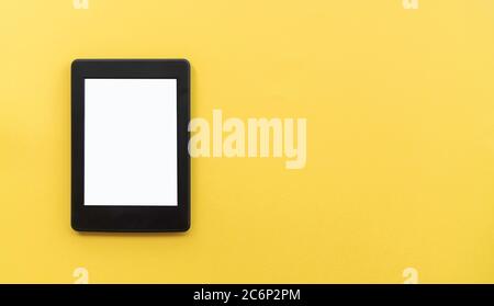 A modern black electronic book with a white blank empty screen on yellow background with empty space Stock Photo