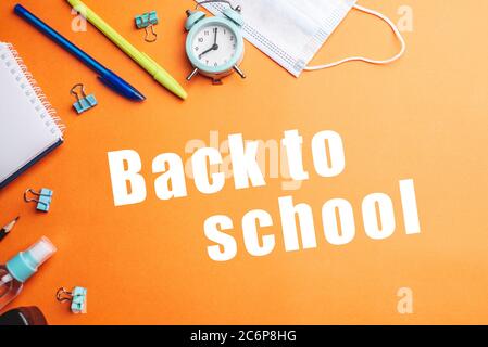 Stationery school supplies around the words Back to school on a orange background. Top view. Stock Photo