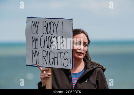 Cleveland, Ohio, USA. 11th July, 2020. THERESA MCINNIS WHITE, co-organzier of the 'Mask Mandate Protest,'' holds her sign, Saturday, July 11, 2020 at Edgewater Park, in Cleveland, Ohio. The City of Cleveland and Cuyahoga County is currently under a red alert, according to the Ohio Public Health Advisory System, which advises wearing a mask while in public and other congregate areas. Governor Mike DeWine enacted the new map-based color coded alert system that helps highlight hot COVID hotspots on a county by county basis. On July 3 Cleveland Mayor Frank G. Jackson amended a Proclamation of St Stock Photo