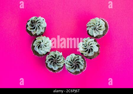 6 cookies and cream cupcakes in a semi-circle viewed from above on a bright pink background Stock Photo