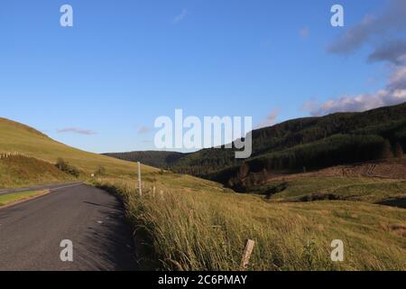 Tarmac road running through green hills and fields  Stock Photo