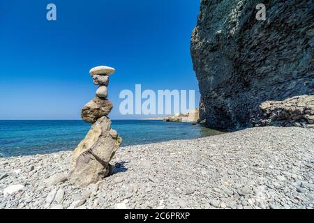 Balanced Pebbles Pyramid on the isolated Beach on Sunny Day and Clear Sky. Blue Sea on Background. Selective focus, Bokeh. Zen stones on sea beach Stock Photo
