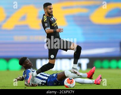 Manchester City's Riyad Mahrez jumps over a challenge from Brighton and Hove Albion's Yves Bissouma during the Premier League match at the Amex Stadium, Brighton. Stock Photo