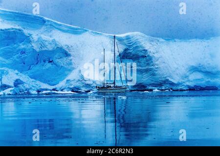 Snowing Sailboat Icebergs Reflection Blue Glacier Snow Mountains Paradise Bay Skintorp Cove Antarctica. Stock Photo
