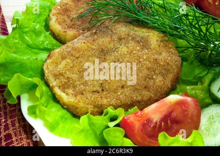 portion of potato cutlets on a plate with vegetables (cucumber, tomato) and greens (lettuce, dill) Stock Photo