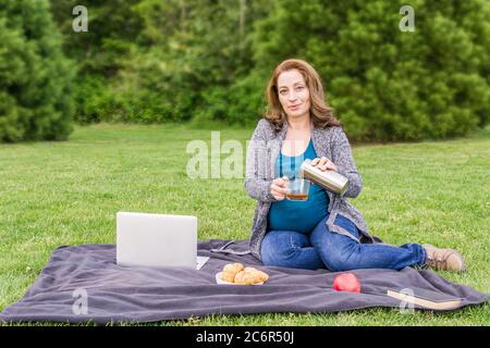 https://l450v.alamy.com/450v/2c6r50j/pregnant-woman-pouring-coffee-otr-tea-from-stainless-thermos-in-the-park-after-working-on-a-computer-2c6r50j.jpg