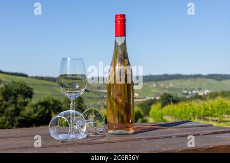 Wine bottle with glasses on wooden table with landscape on river moselle in background Stock Photo