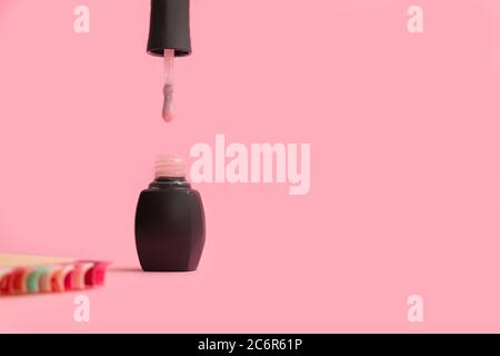 Opened pink nail polish bottle om soft pink background. Nail polish cosmetics concept Stock Photo