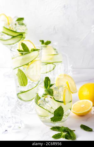 Alcohol drink (gin tonic cocktail) in a variety of glasses with lemon, cucumber, mint leaves and ice on white. Iced drink with lemon. Stock Photo