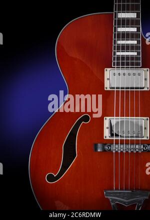 Detail of an Ibanez AF75 Hollowbody Electric Guitar in transparent orange showing the soundhole, humbucker pickups, bridge and tail piece, binding, pearl inlays, and fretboard. Stock Photo