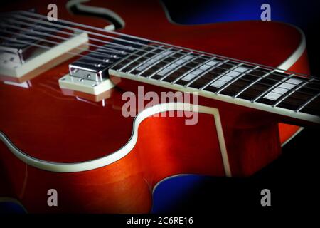 Detail of an Ibanez AF75 Hollowbody Electric Guitar in transparent orange showing the cutaway, humbucker pickups, fretboard, and binding. Stock Photo