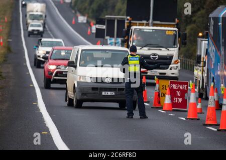 Melbourne, Australia 11 July 2020, a police officer directs traffic into one of the roadblocks on the Western Highway in Victoria, established in an effort to try to contain the spread of the corona virus in Australia’s second most populous state. Credit: Michael Currie/Alamy Live News