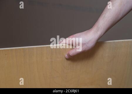 hand holds a piece of plywood work in the attic Stock Photo