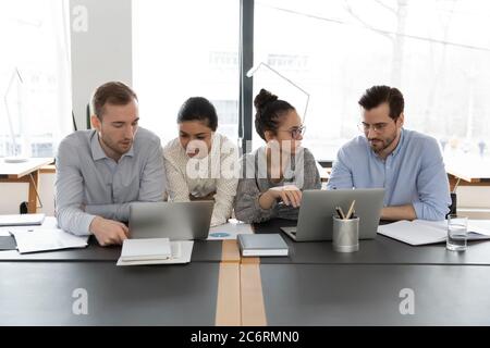 Multiracial employees work in groups using laptops at meeting Stock Photo