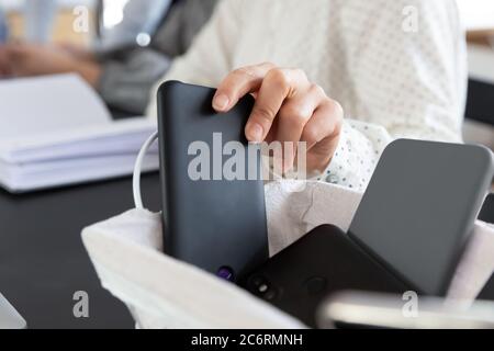 Close up of employee put cellphone in box at meeting Stock Photo