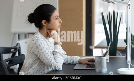 Pensive indian female employee look in distance thinking Stock Photo