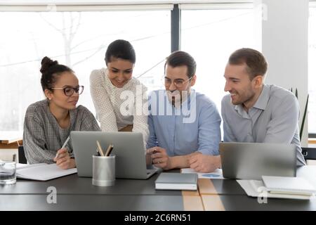 Smiling multiracial employees work on laptop in office Stock Photo