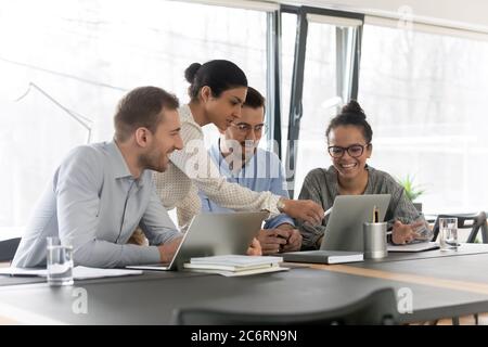 Smiling diverse colleagues cooperate using laptop together Stock Photo