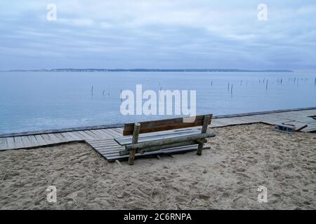 wooden winter bench view over Arcachon Bay basin in France near Cap Ferret with Dune du Pilat Pyla background in sunrise Stock Photo