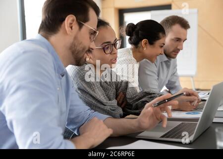 Focused diverse employees work on laptops at meeting Stock Photo