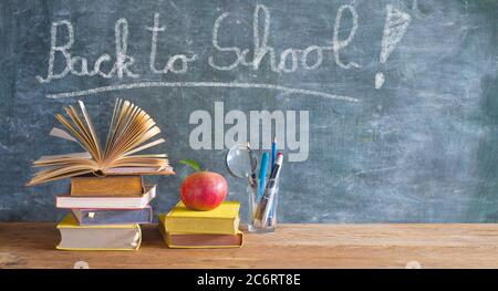 Back to school after the coronavirus lockdown, education supplies, books, pens, message on blackboard Stock Photo